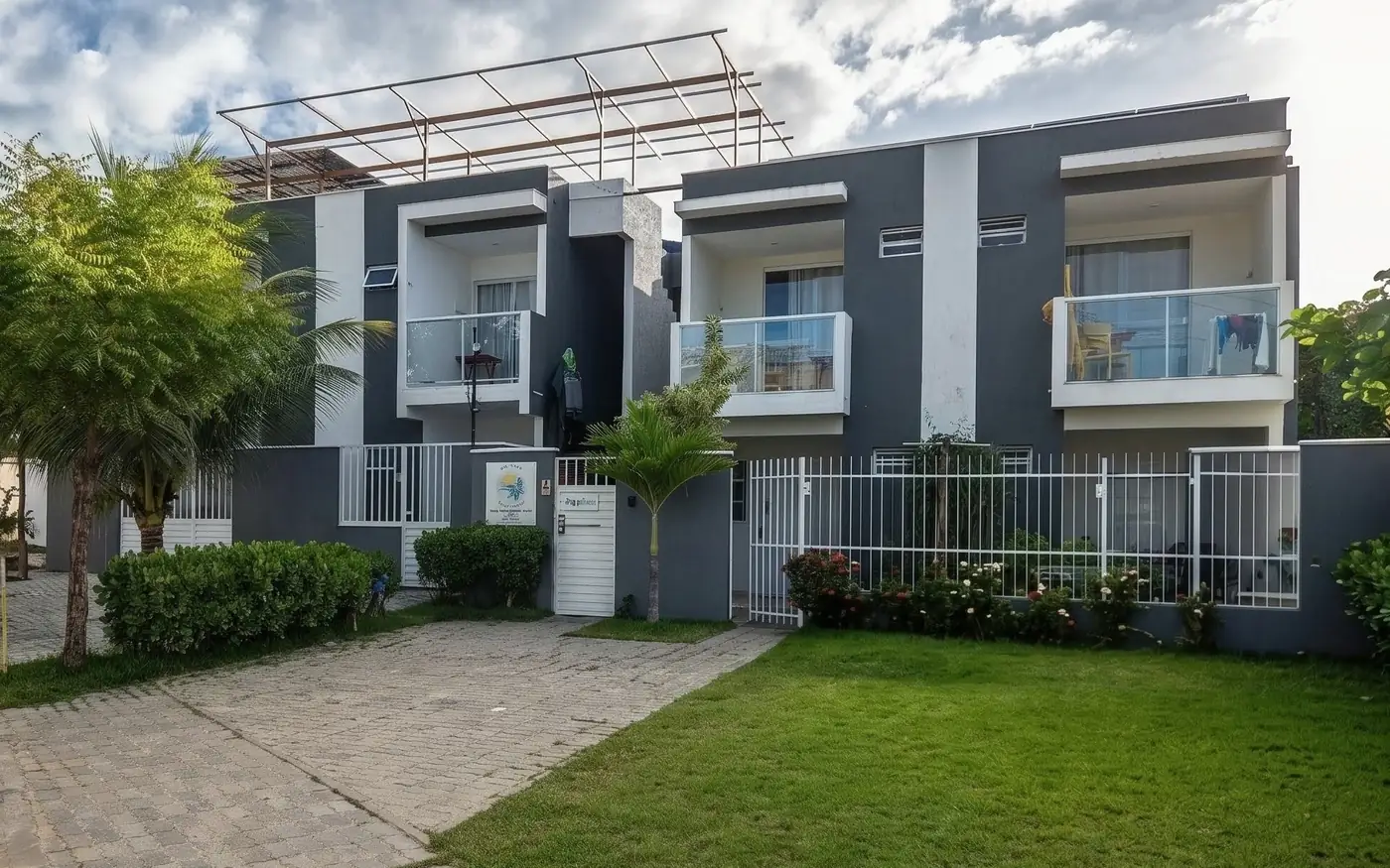 Fachada da MS Flats em Paripueira, com as varandas dos flats superiores, o portão de entrada e o jardim da propriedade
